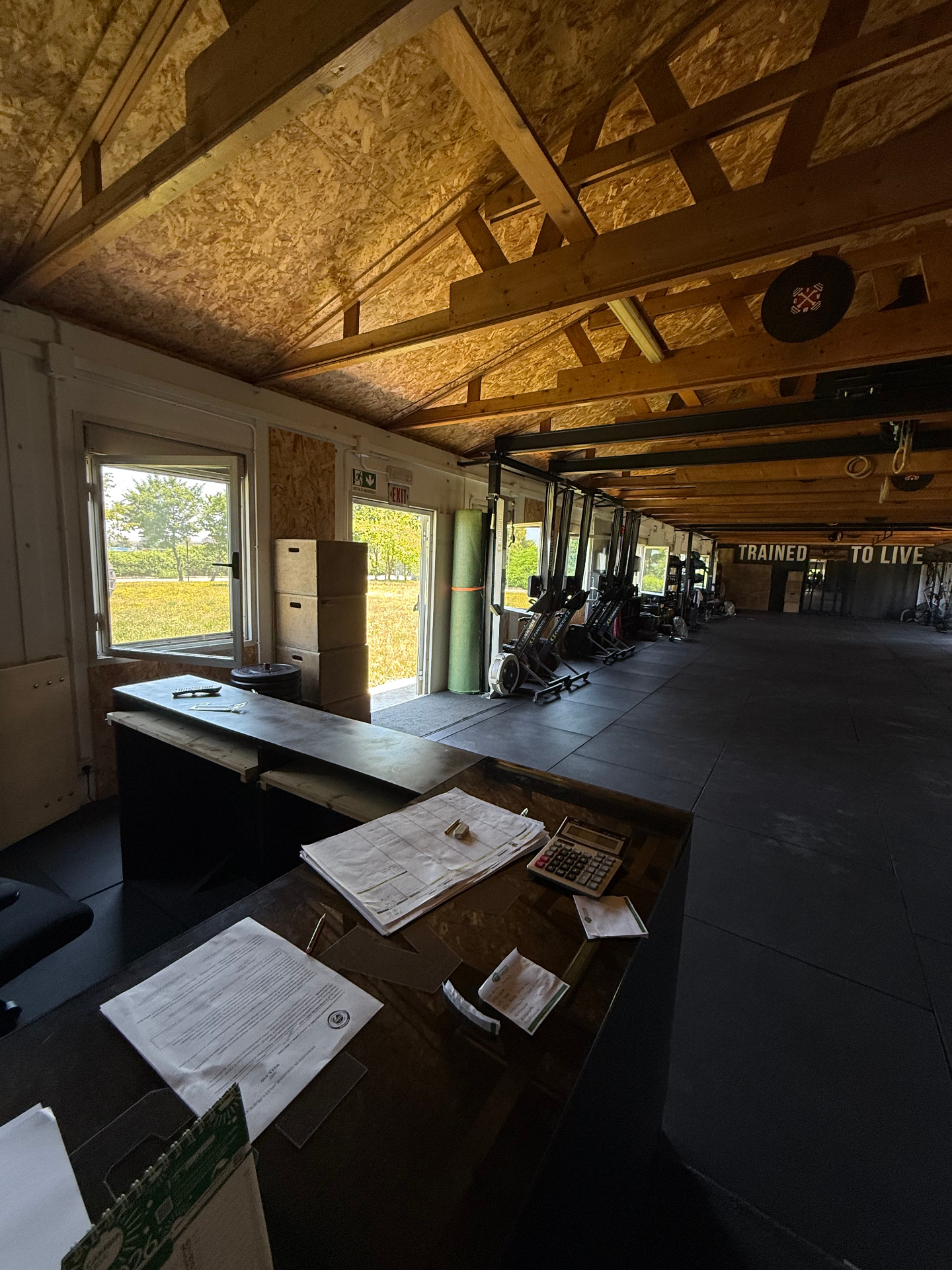 Reception e vista sala con scritta Trained to Live